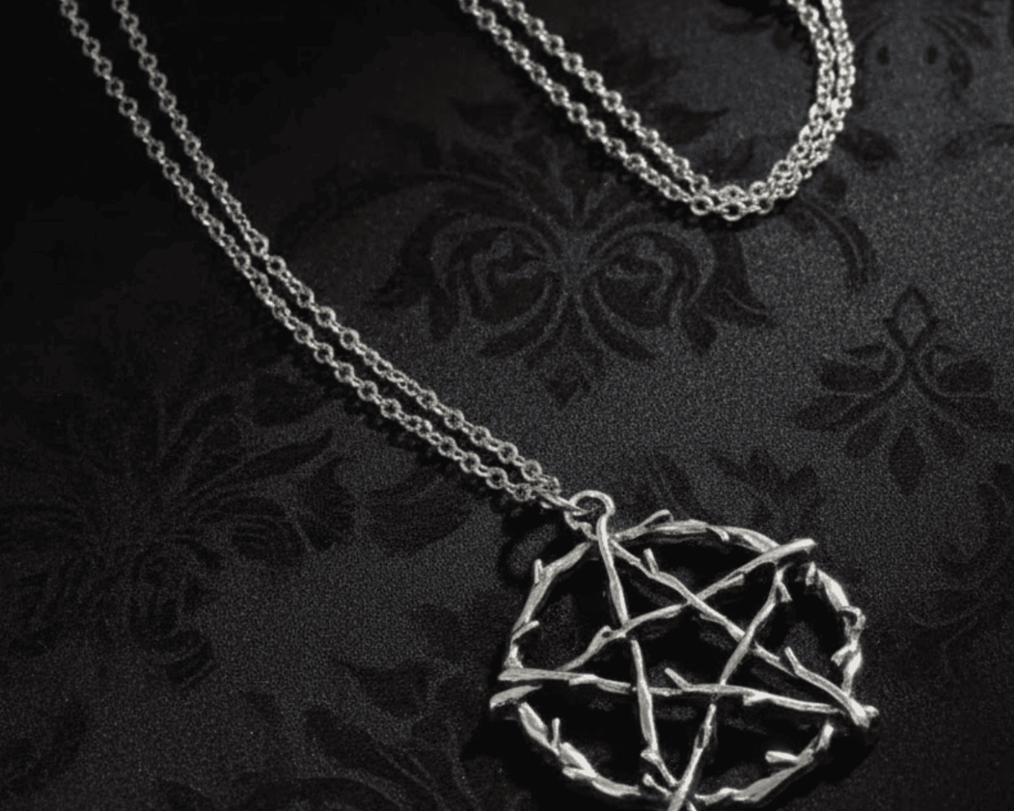 Silver necklace with a pentagram pendant on a dark textured background