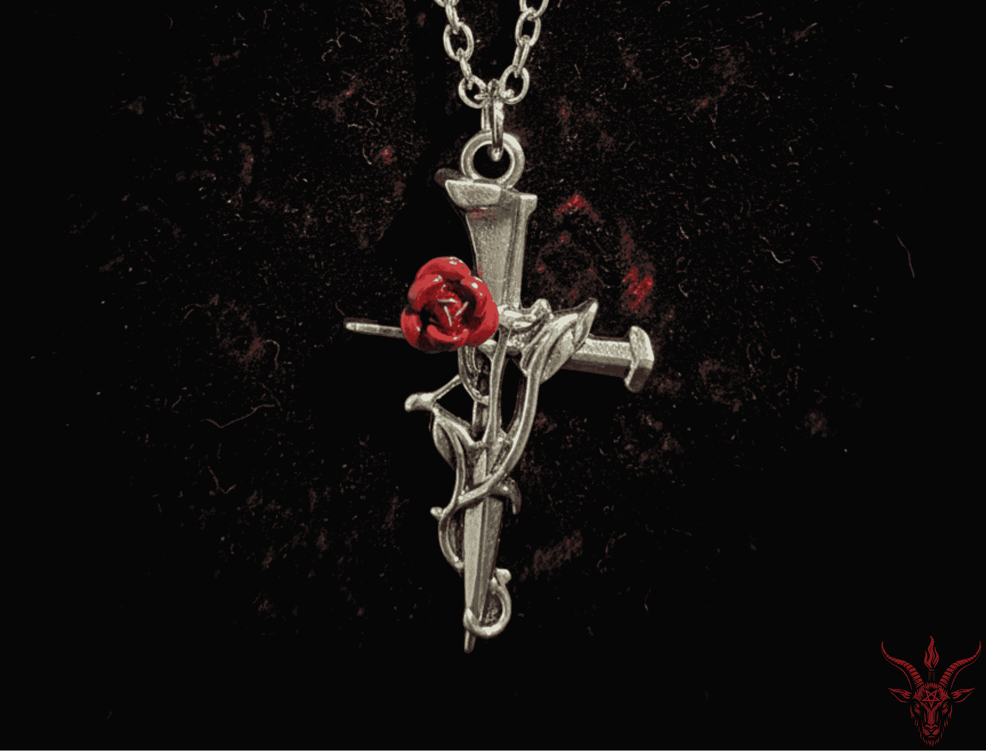 Silver cross pendant with a red rose on a dark background